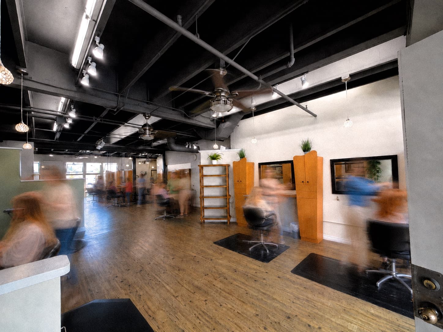 The salon floor mid-service, stylists and clients blurred with movement
